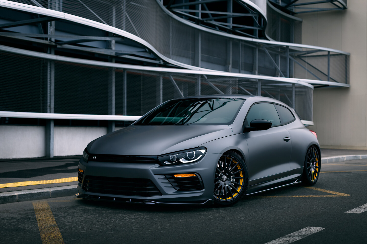 Modified sports car with matte gray finish and gold wheels parked in modern garage