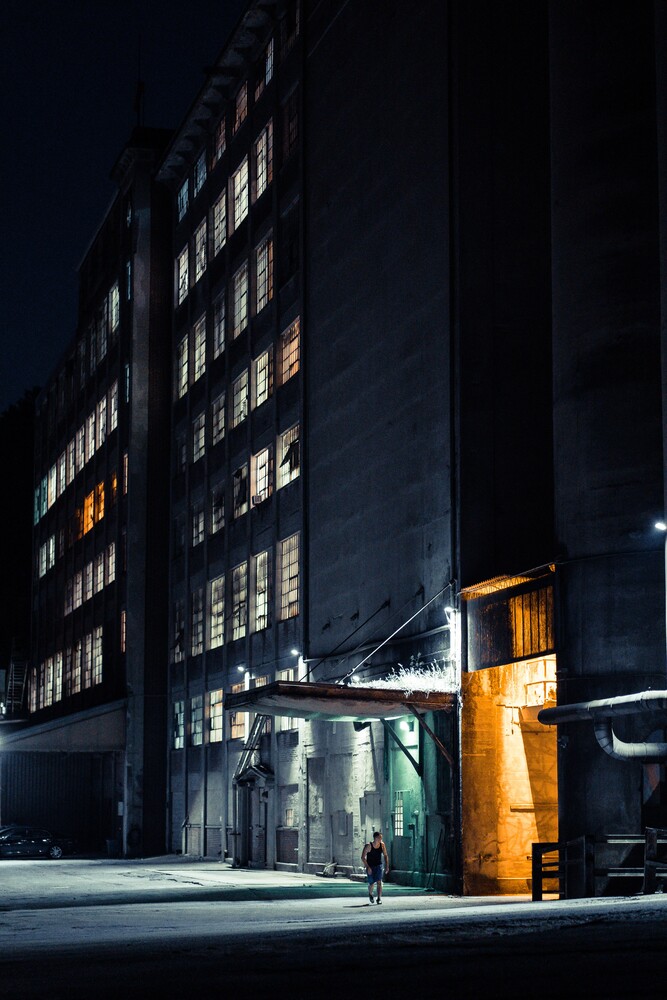 Nighttime urban street scene with illuminated storefront and multi-story office building