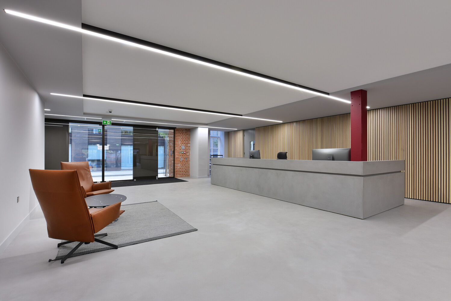 Modern office lobby with reception desk, leather chair, and floor-to-ceiling windows