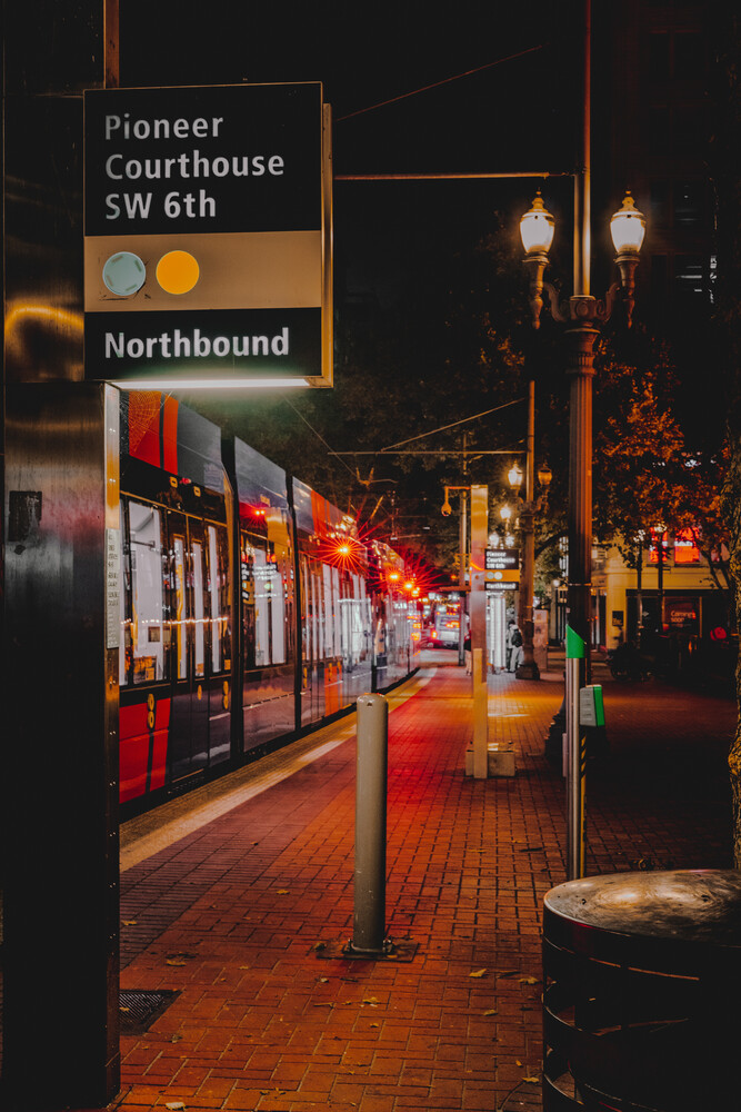 Pioneer Courthouse SW 6th street sign illuminated at night with storefront and street lamps
