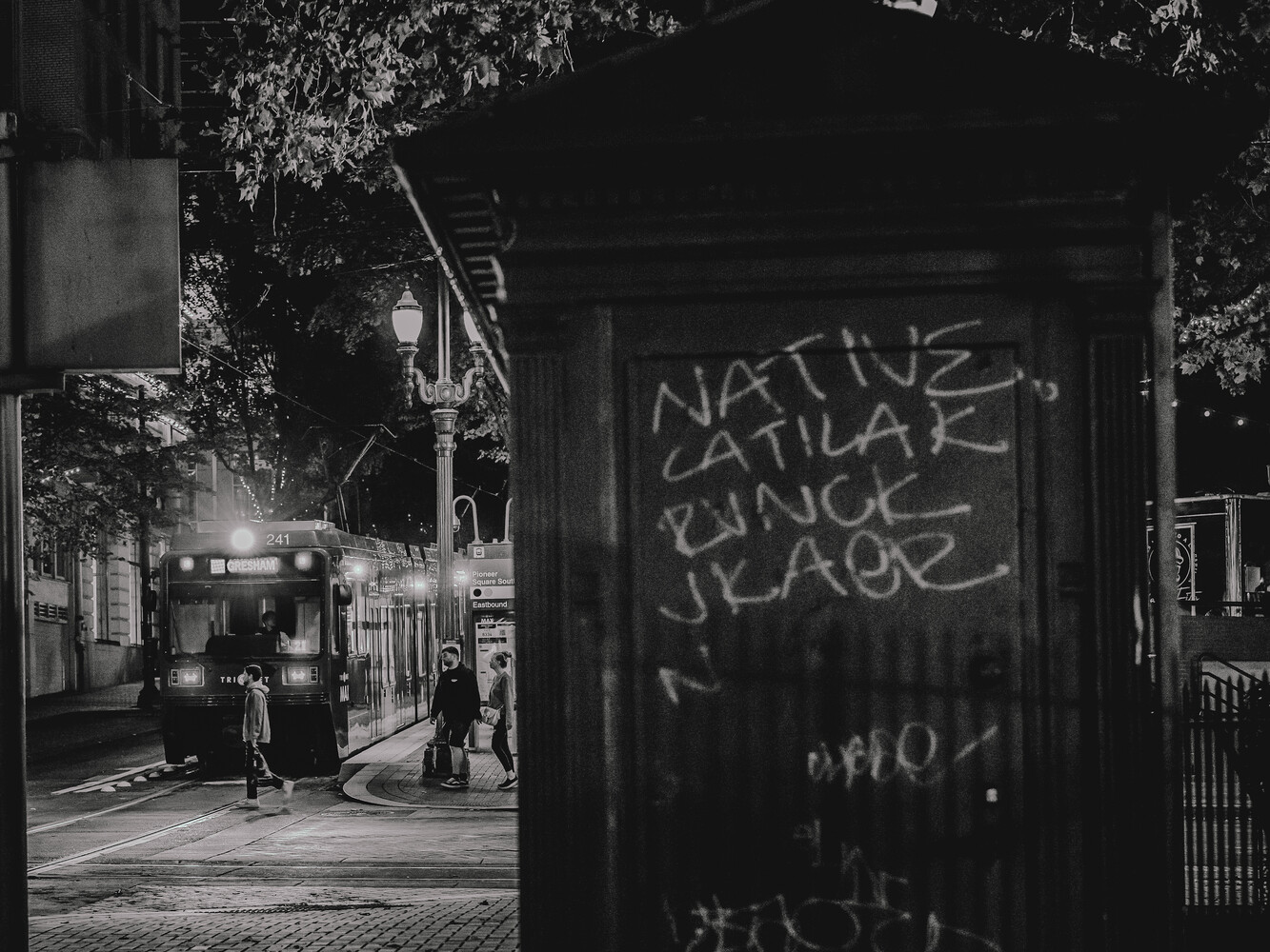 Nighttime street scene with graffitied storefront and pedestrians in urban alley