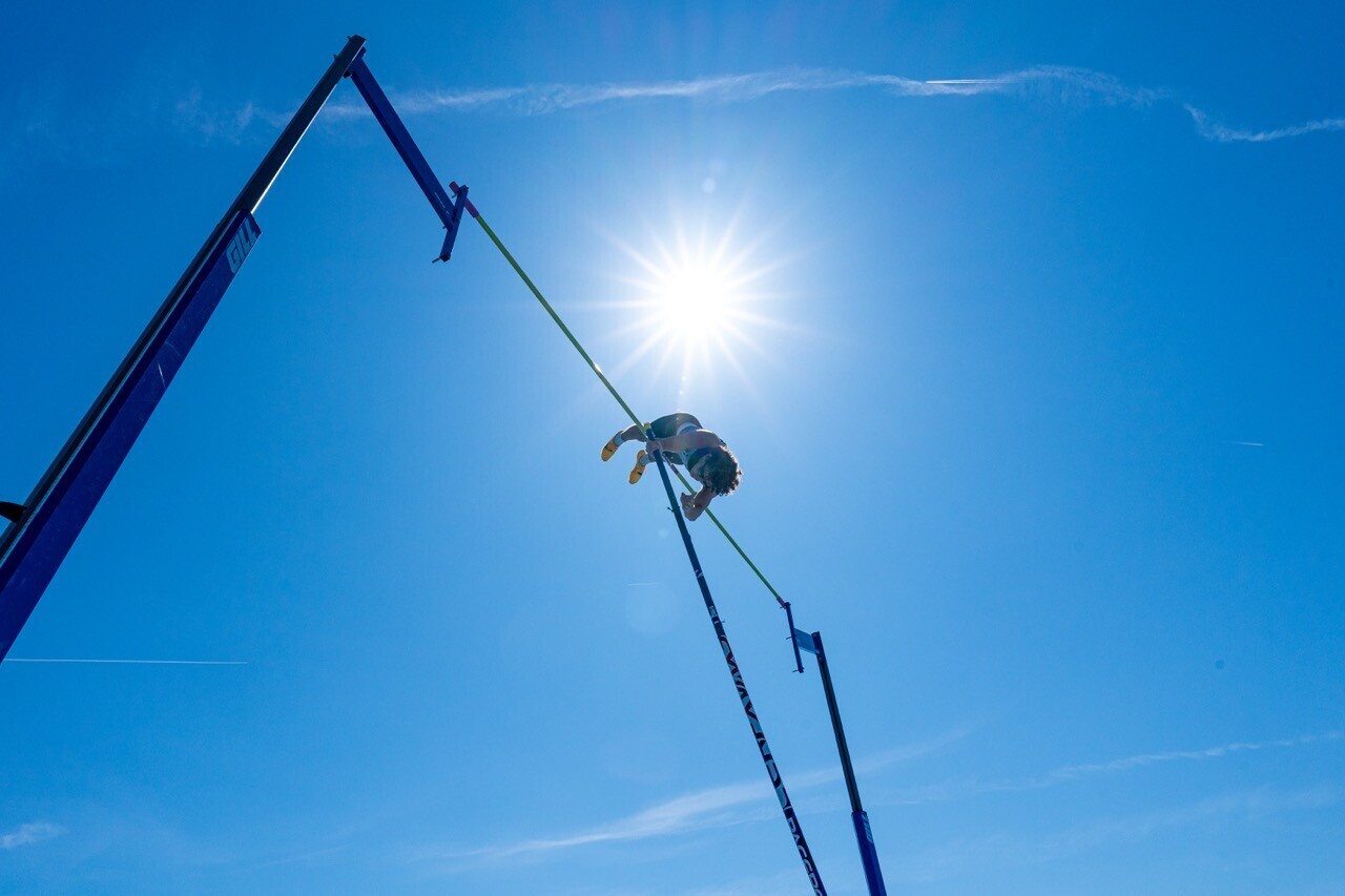 Person suspended on rope against bright sun and clear blue sky during rope descent