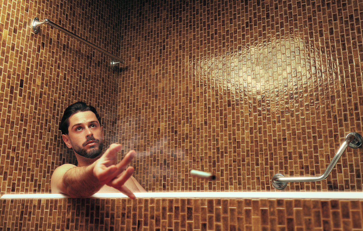 Man bathing in a brick-tiled bathroom with warm overhead lighting