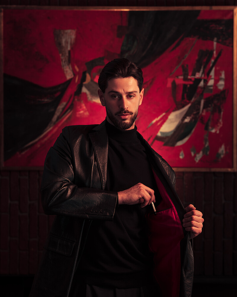 Man in black jacket against vibrant red and black abstract background