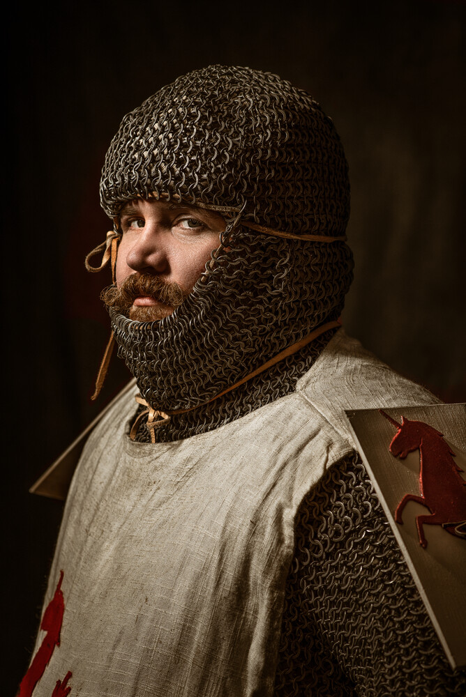 Medieval warrior in chainmail coif and tunic with red cross emblem