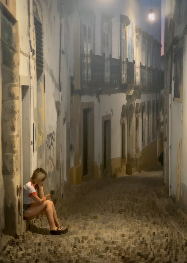 Seated figure in narrow European alleyway lit by warm evening light