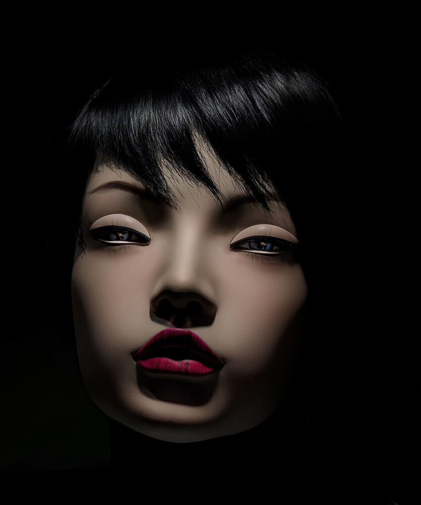 High-contrast portrait of a stylized face with dark hair and bold red lips against black background