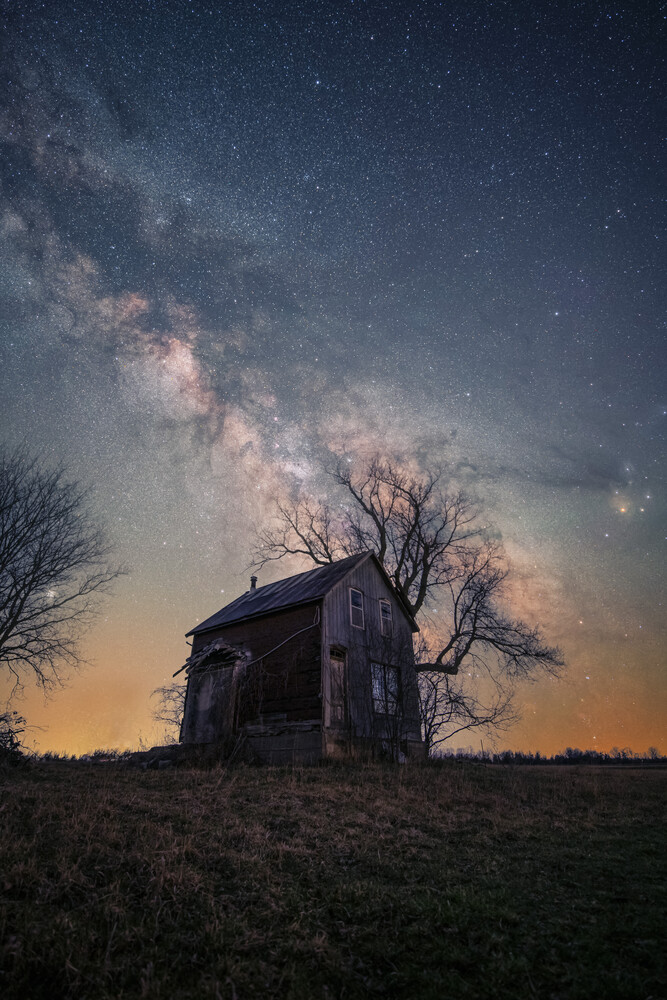 Abandoned two-story house under the Milky Way galaxy at night