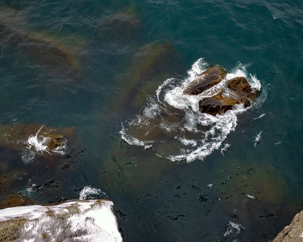 View Rocks at the Bottom of a Cliff by Jonathan Baird
