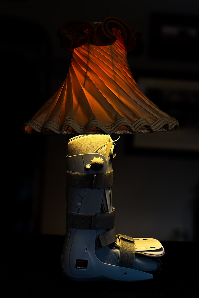 Yellow toy car illuminated beneath an orange pleated lampshade in dark studio setting