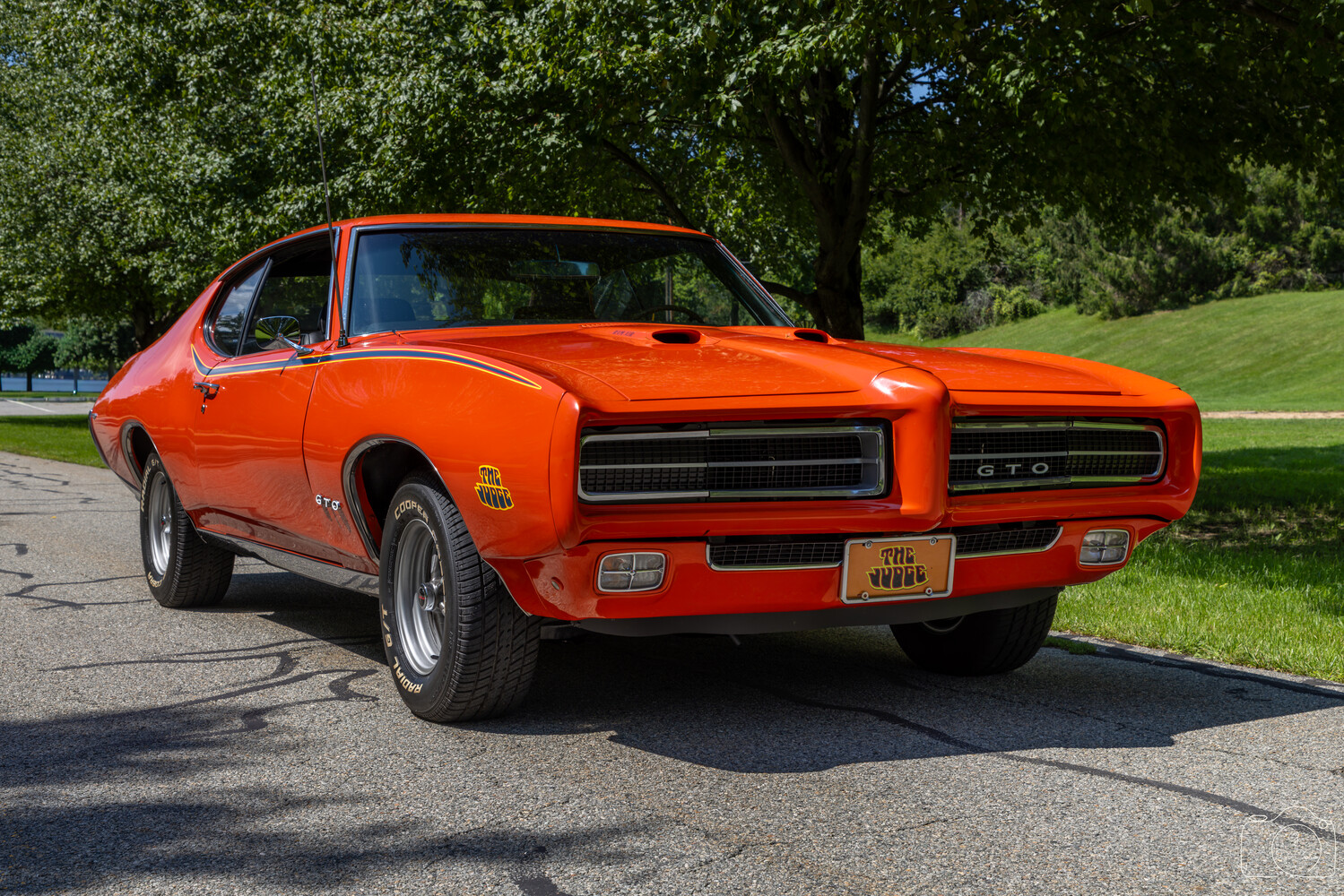 Bright orange 1970s GTO muscle car photographed outdoors in natural daylight