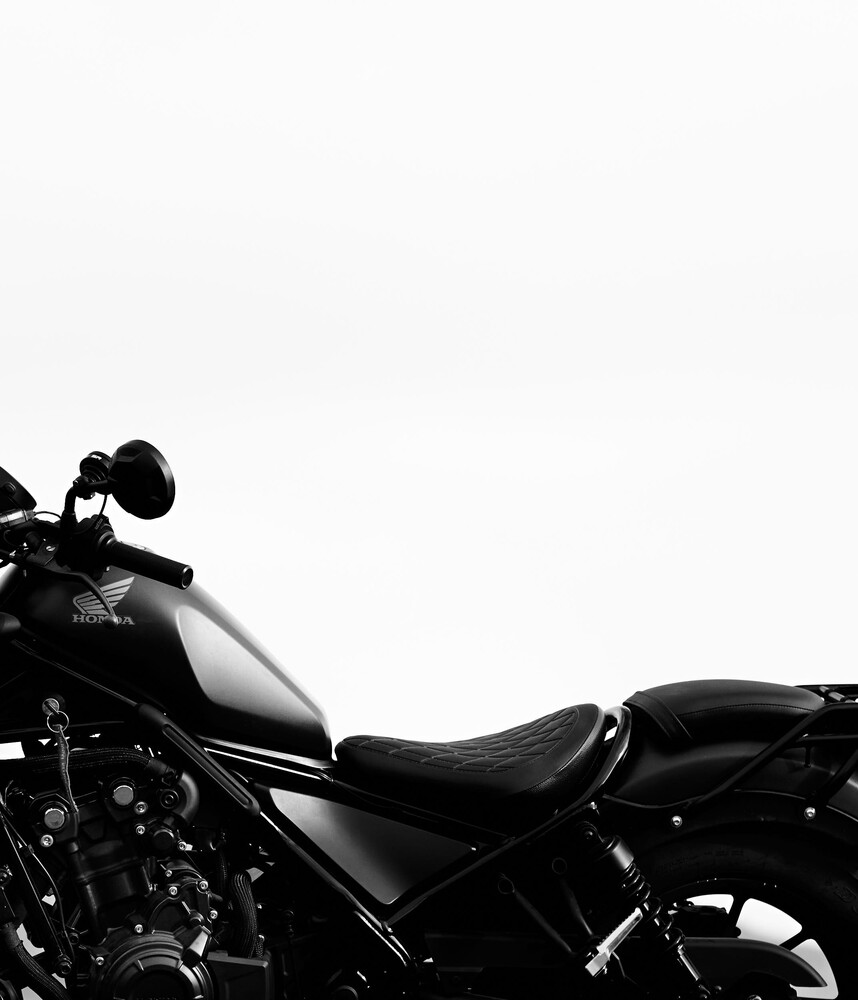 Black motorcycle silhouetted against white background with headlight and seat visible