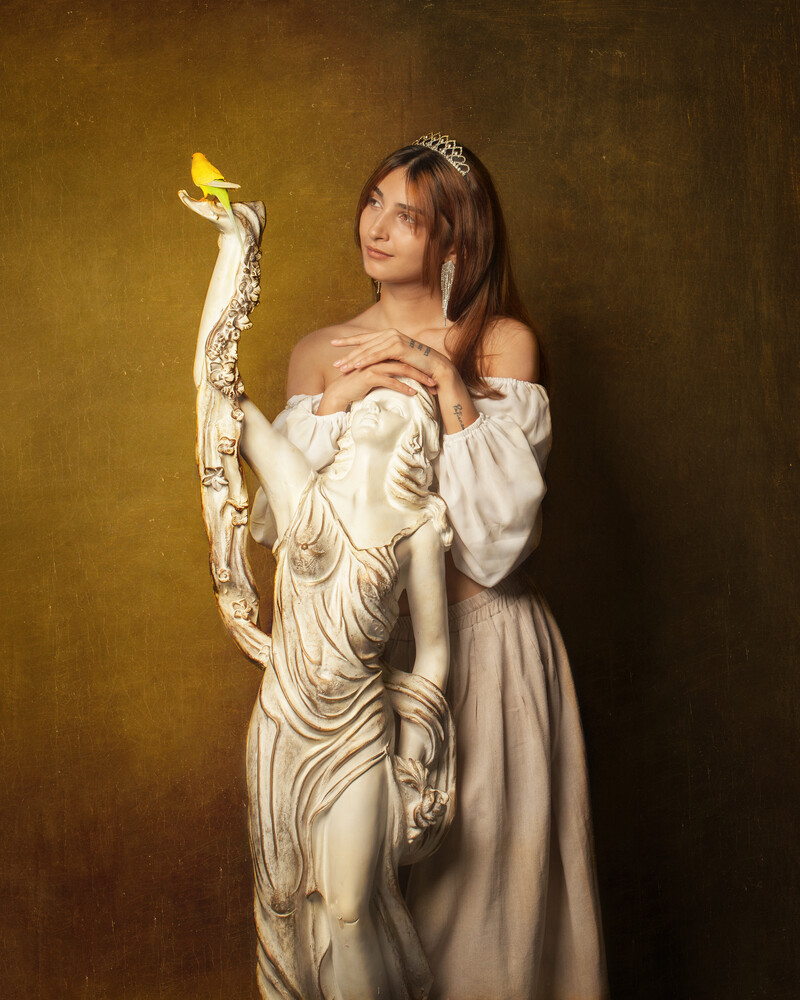 Woman in cream off-shoulder dress holding ornate white swan sculpture with gold accents