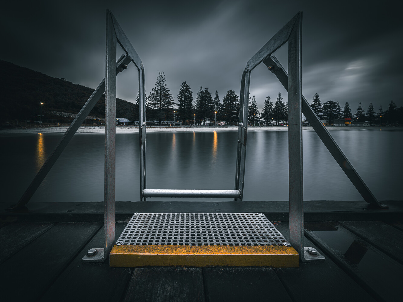 Symmetrical view through metal dock gates framing a misty lake with evergreen forest