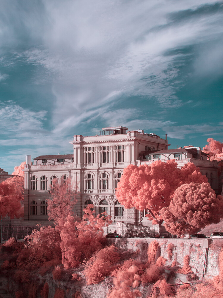 Grand neoclassical mansion with pink foliage under turquoise sky in infrared photography