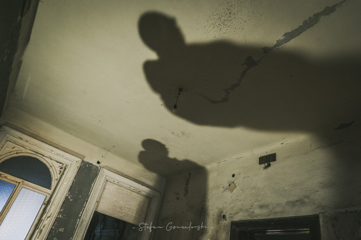 Shadows of two people cast on a deteriorating ceiling with peeling paint