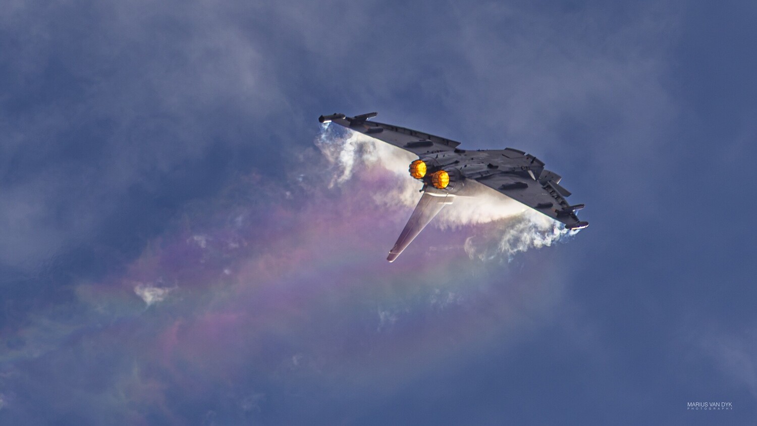 Military fighter jet executing a high-G maneuver with visible vapor clouds and afterburner glow