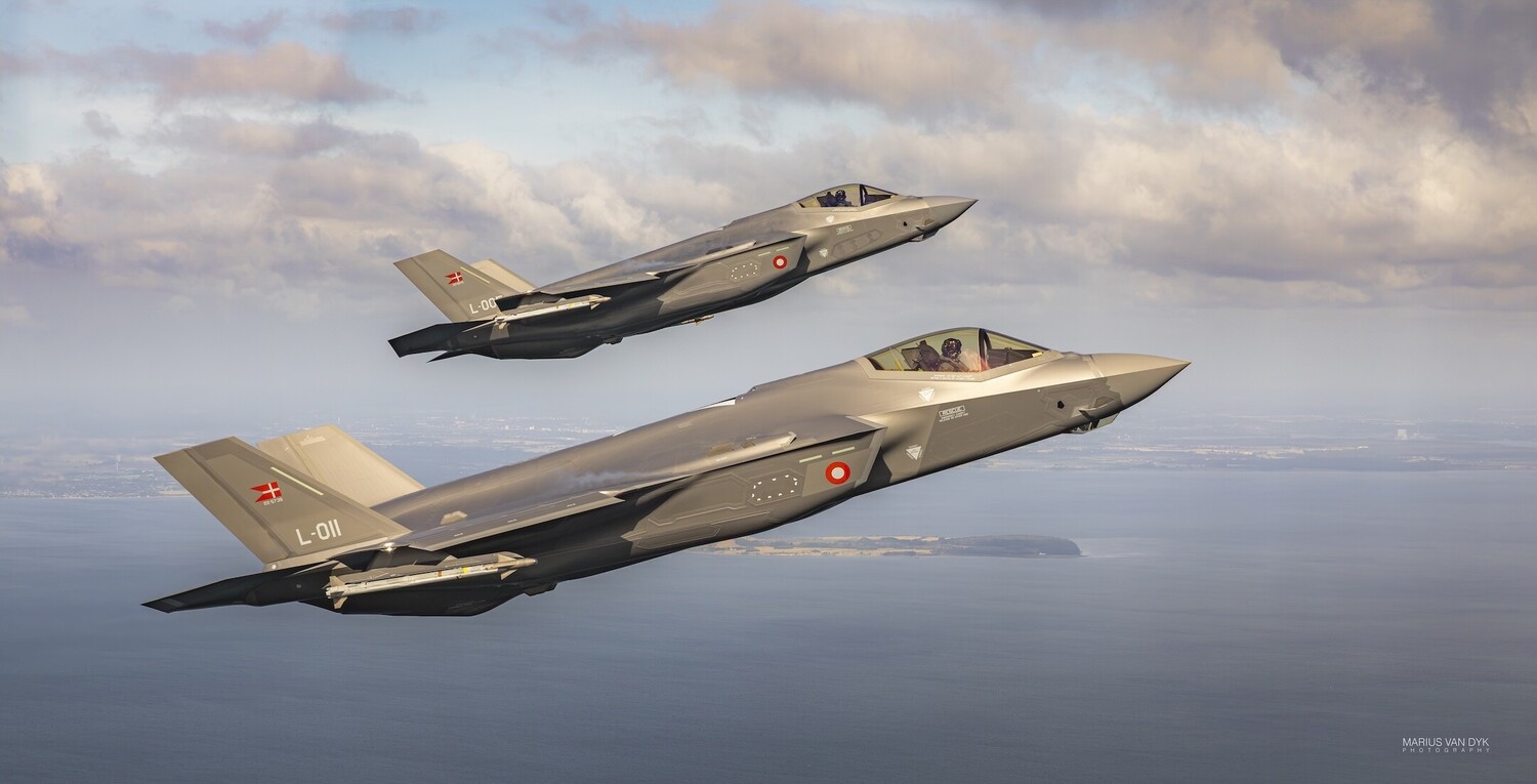 Illustration of two F-35 stealth fighter jets in formation flight over water