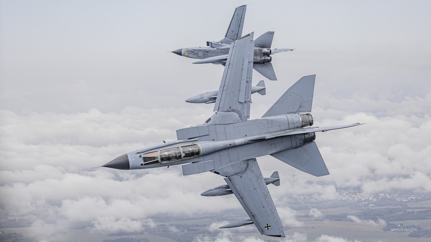 Two military fighter jets in formation flight above clouds