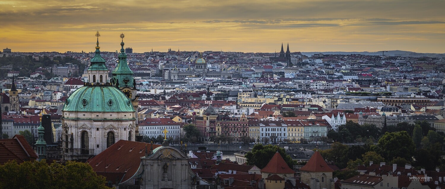 Prague cityscape at golden hour with Church of St. Nicholas dome in foreground