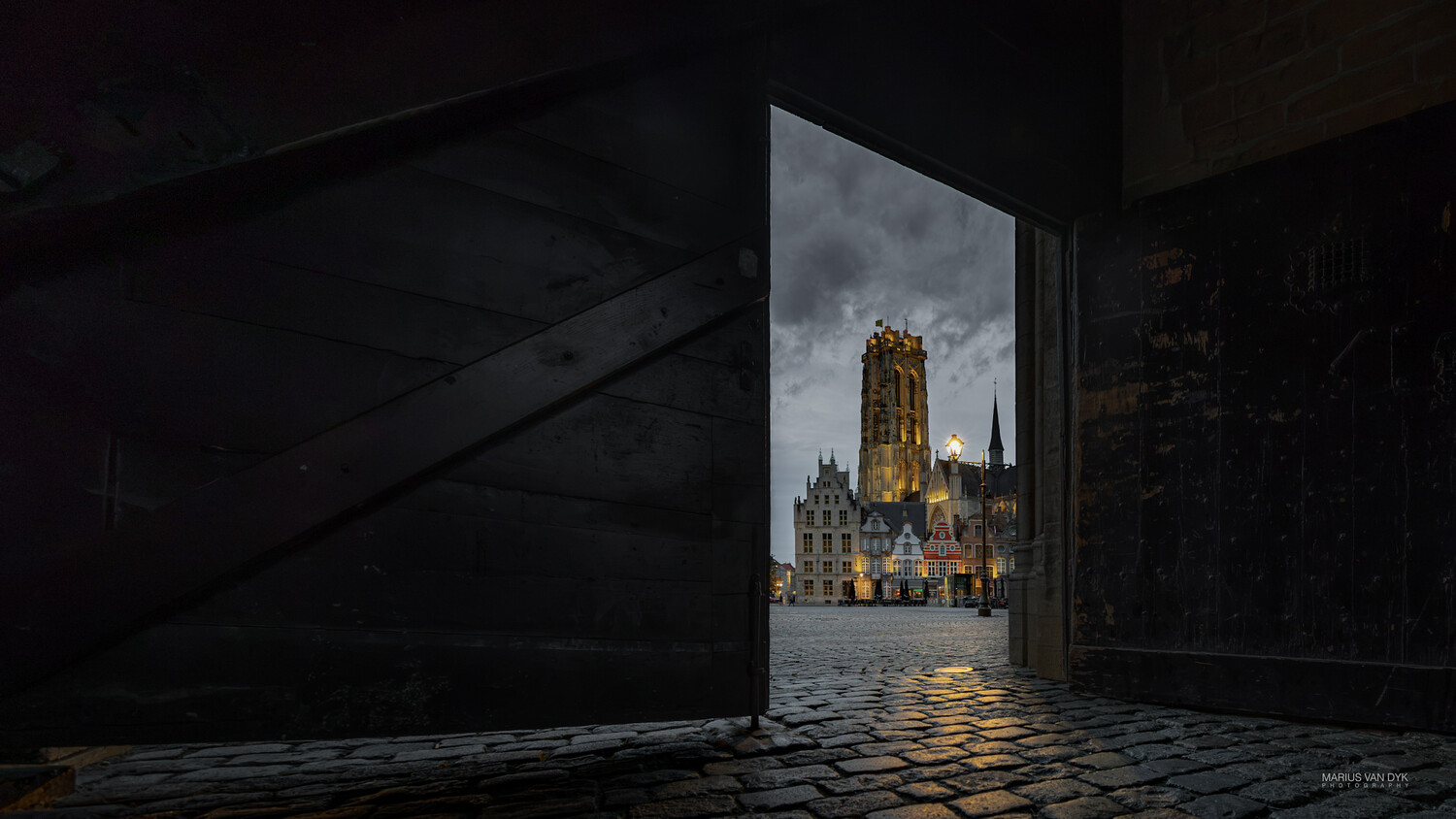 Medieval cathedral illuminated at dusk, viewed through a dark stone archway