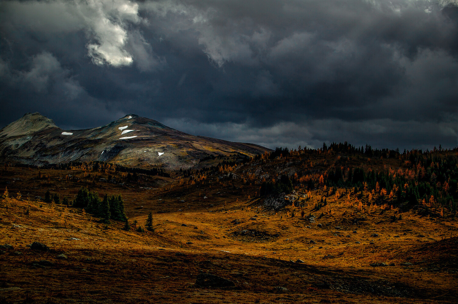 Mountain landscape with golden hillside beneath dramatic storm clouds