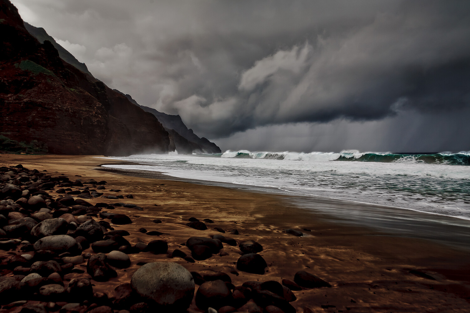 Rocky beach with dramatic storm clouds rolling over turbulent ocean waves and steep coastal cliffs
