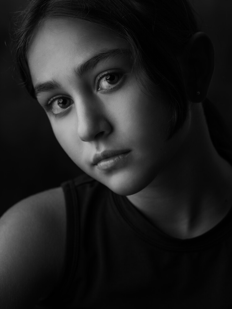 Black and white portrait of a woman with direct gaze in dramatic side lighting