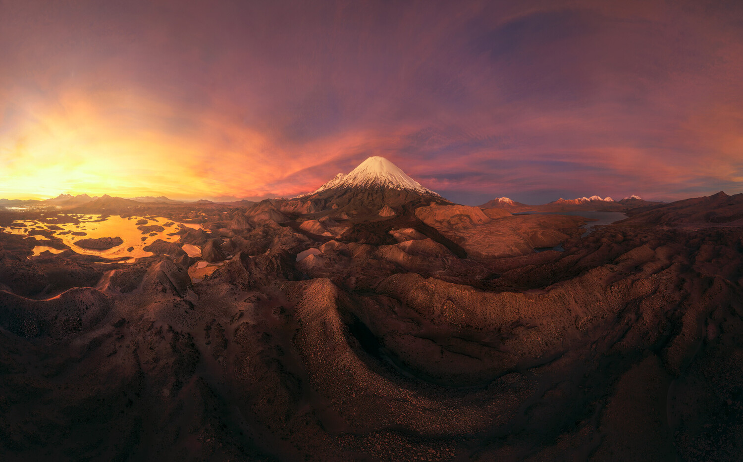 Snow-capped volcanic cone at sunset with dramatic orange and purple sky
