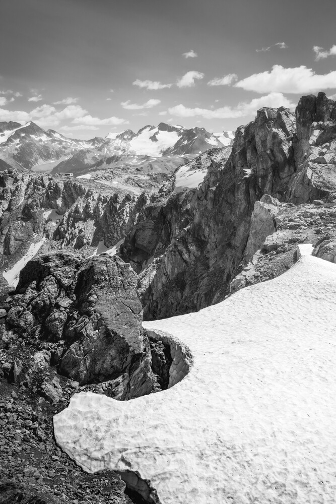 Alpine peaks with dramatic rock formations and patches of snow in a black and white mountain landscape
