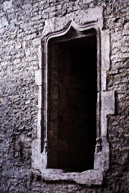 Weathered rectangular doorway with dark interior set into textured stone wall