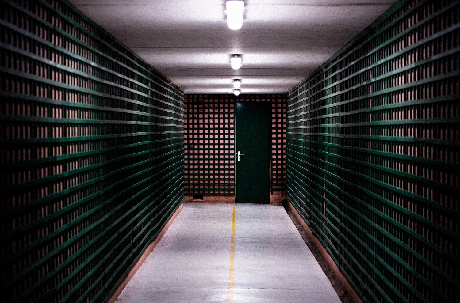 Symmetrical corridor lined with server racks stretching toward a red door