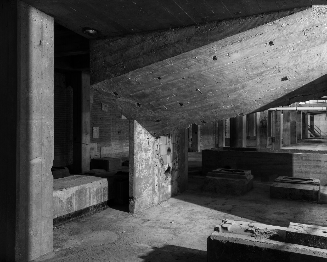 Black and white photograph of brutalist concrete interior space with geometric pillars and beams