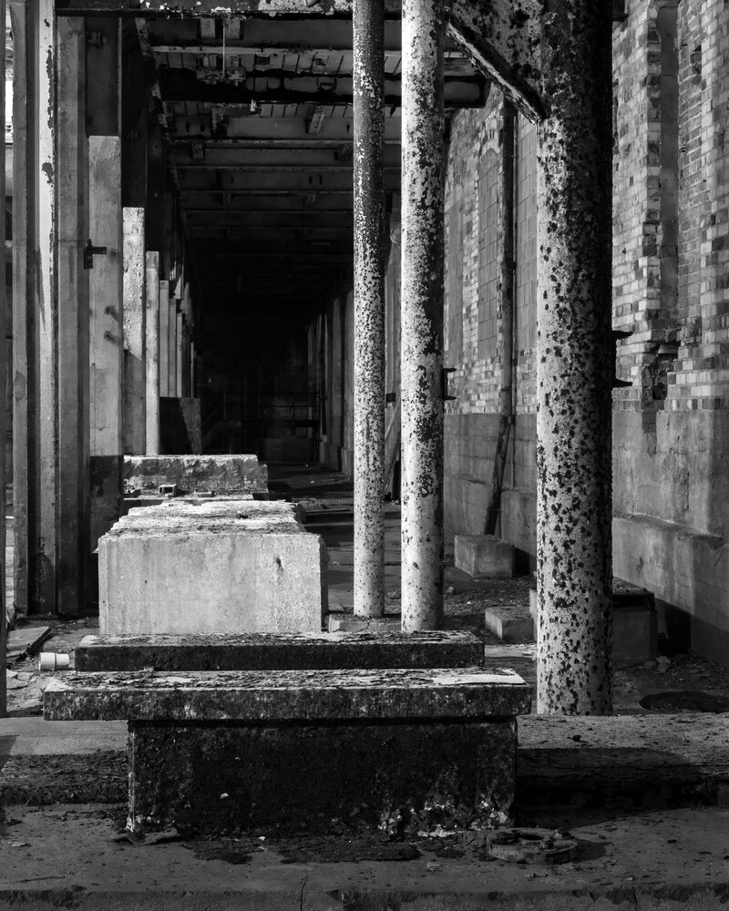 Deteriorated concrete columns and walls in an abandoned corridor with deep perspective