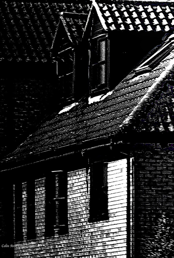 High-contrast black and white photograph of brick building with diagonal roof lines and windows