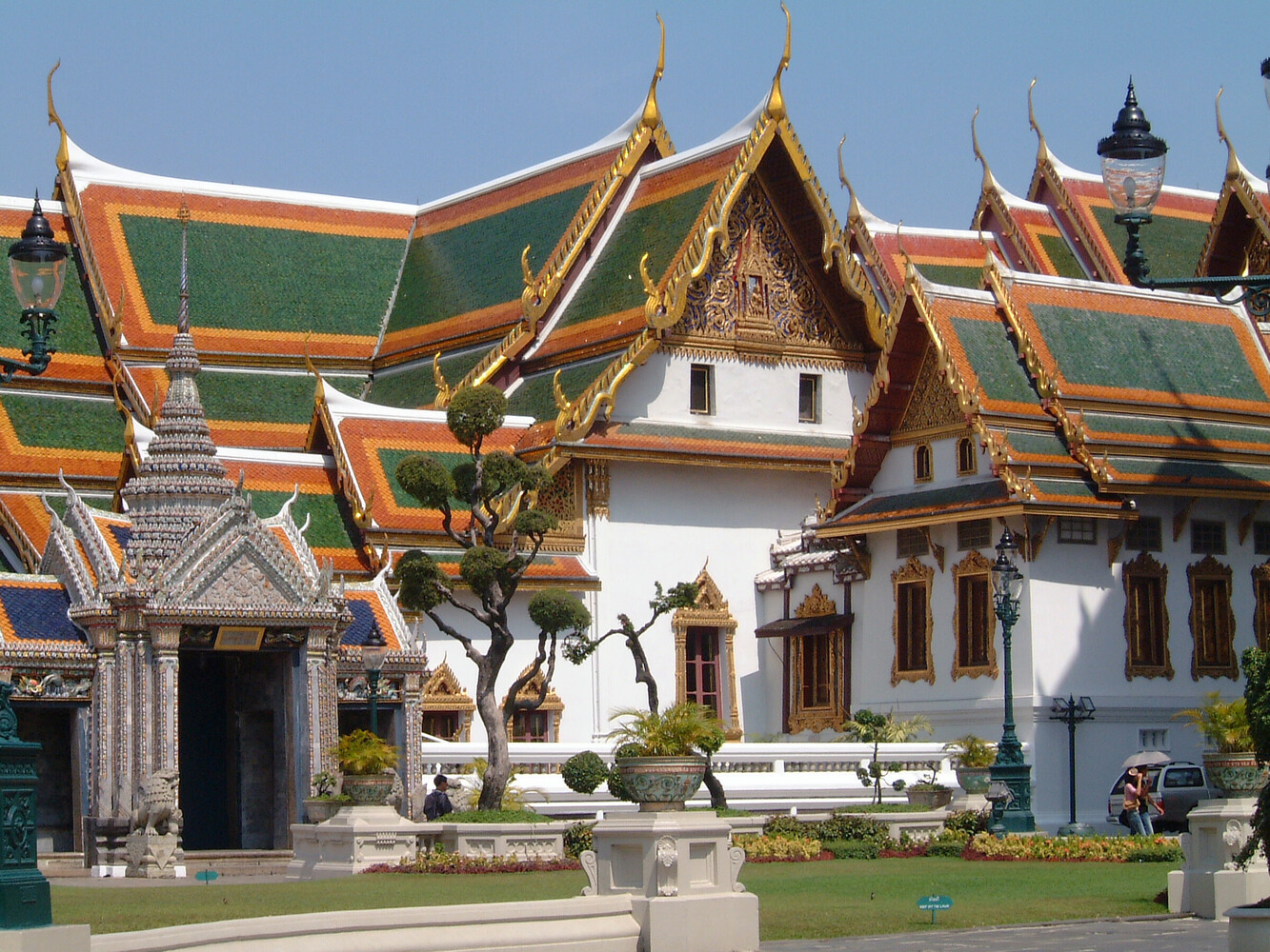 Thai Buddhist temple with ornate green-tiled roofs and golden spires under clear blue sky