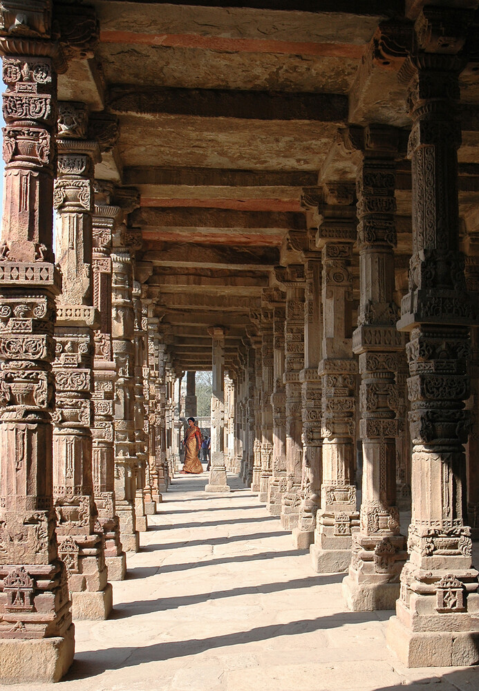 Colonnade of intricately carved stone pillars extending into distance with strong linear perspective