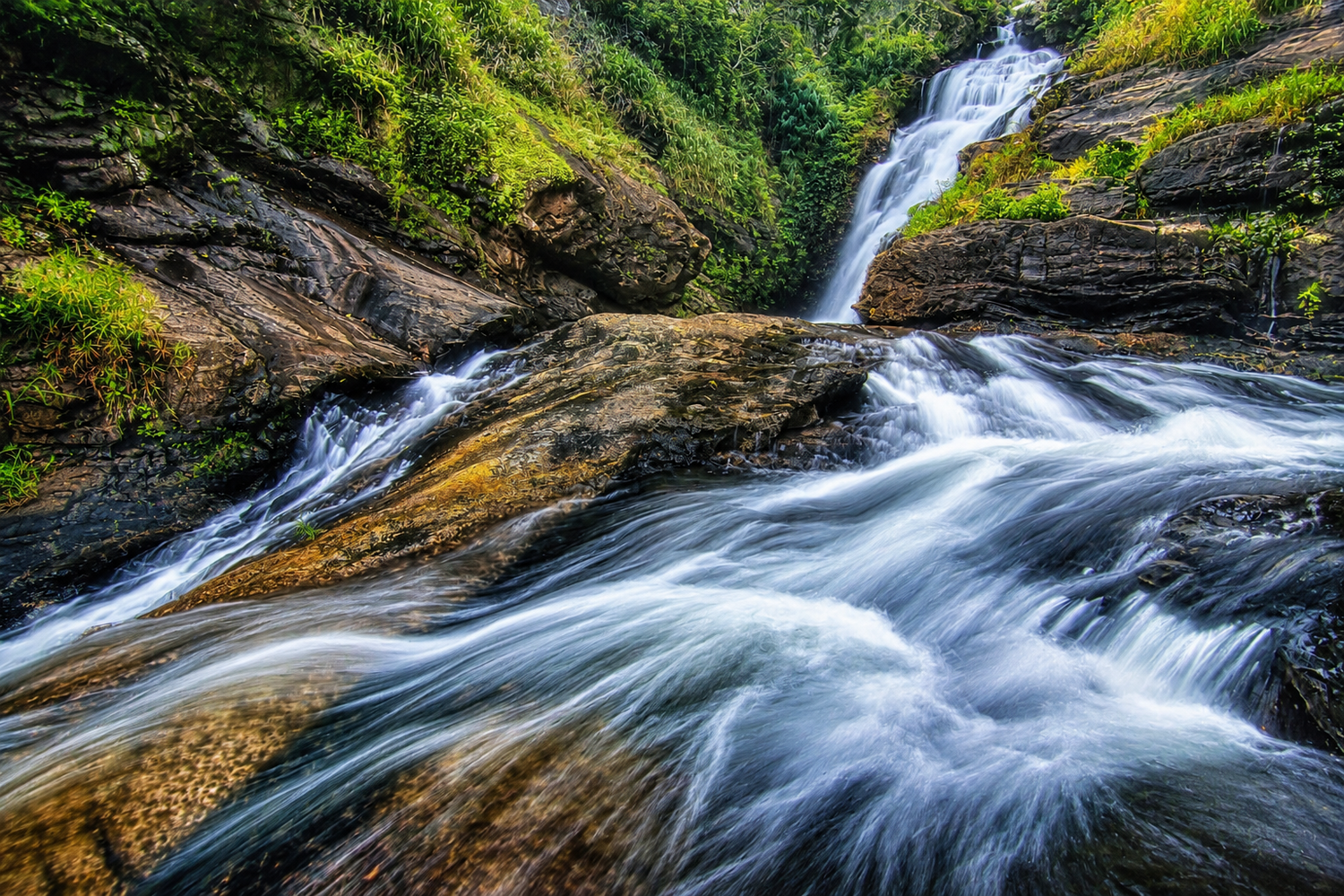 Cascading mountain stream with long exposure blur flowing over moss-covered rocks