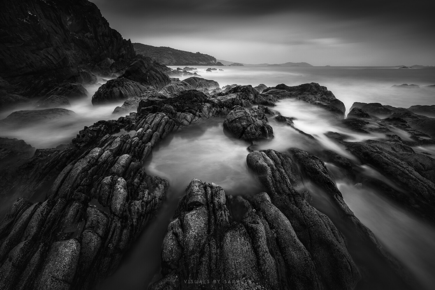 Rocky coastal shoreline with columnar basalt formations and silky water from long exposure