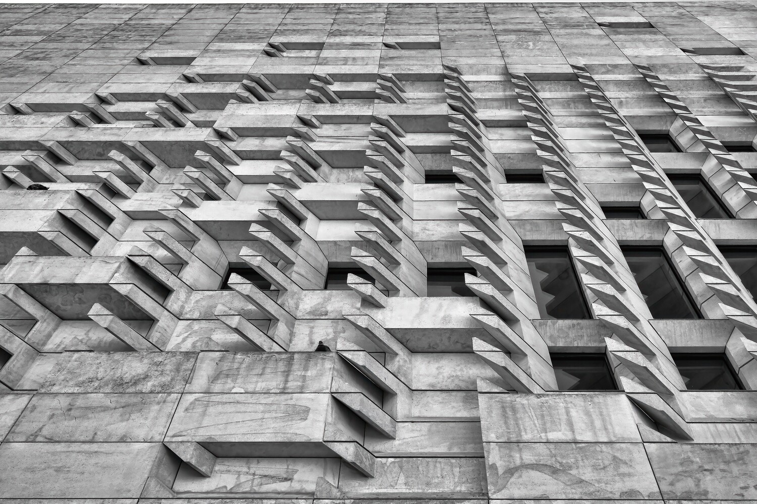 Black and white photograph of a brutalist apartment building facade with repetitive geometric balconies and windows