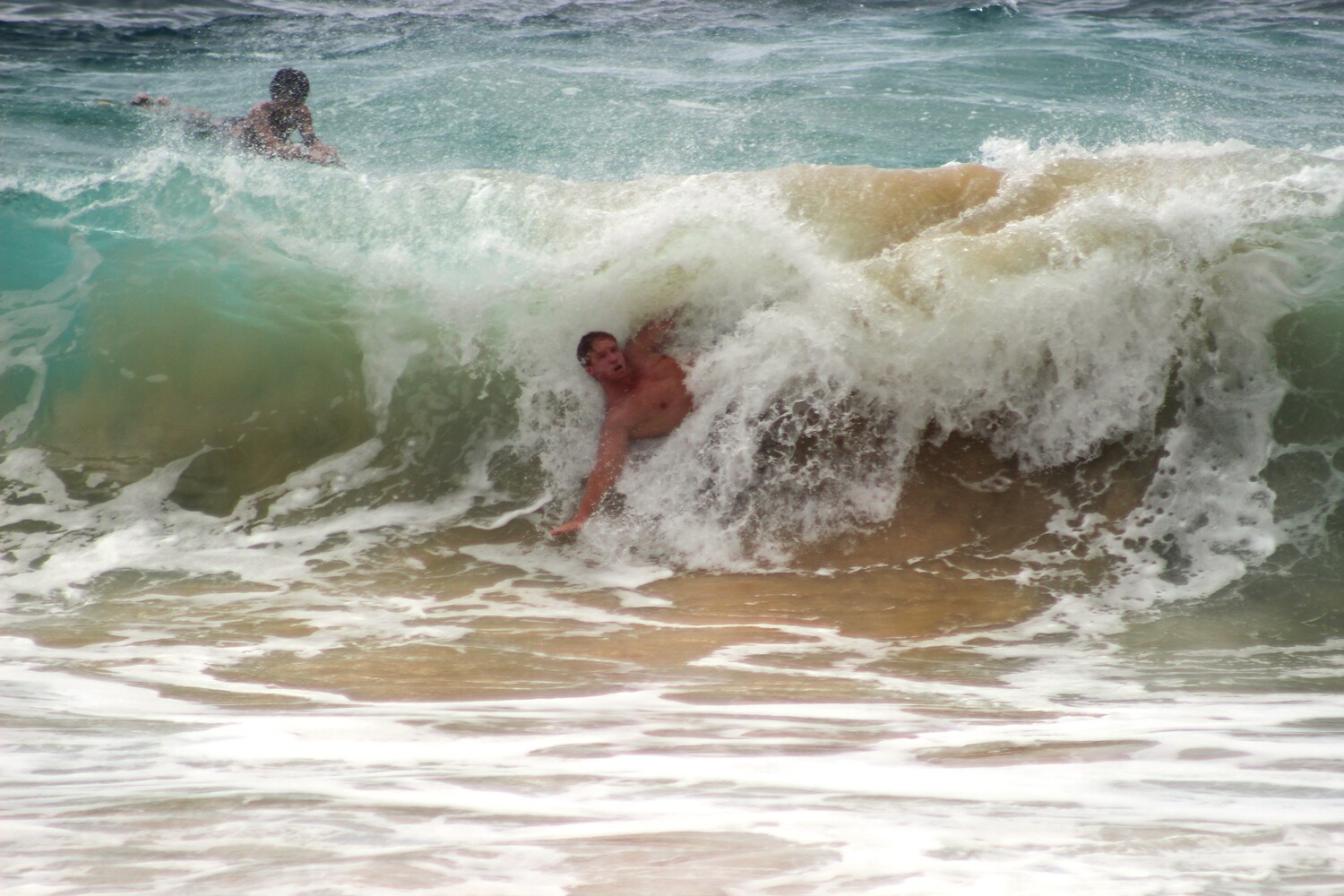 Bodyboarder riding a wave in turquoise ocean water near shore
