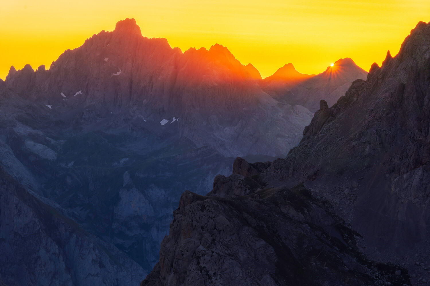 Dramatic mountain peaks silhouetted against golden sunrise sky