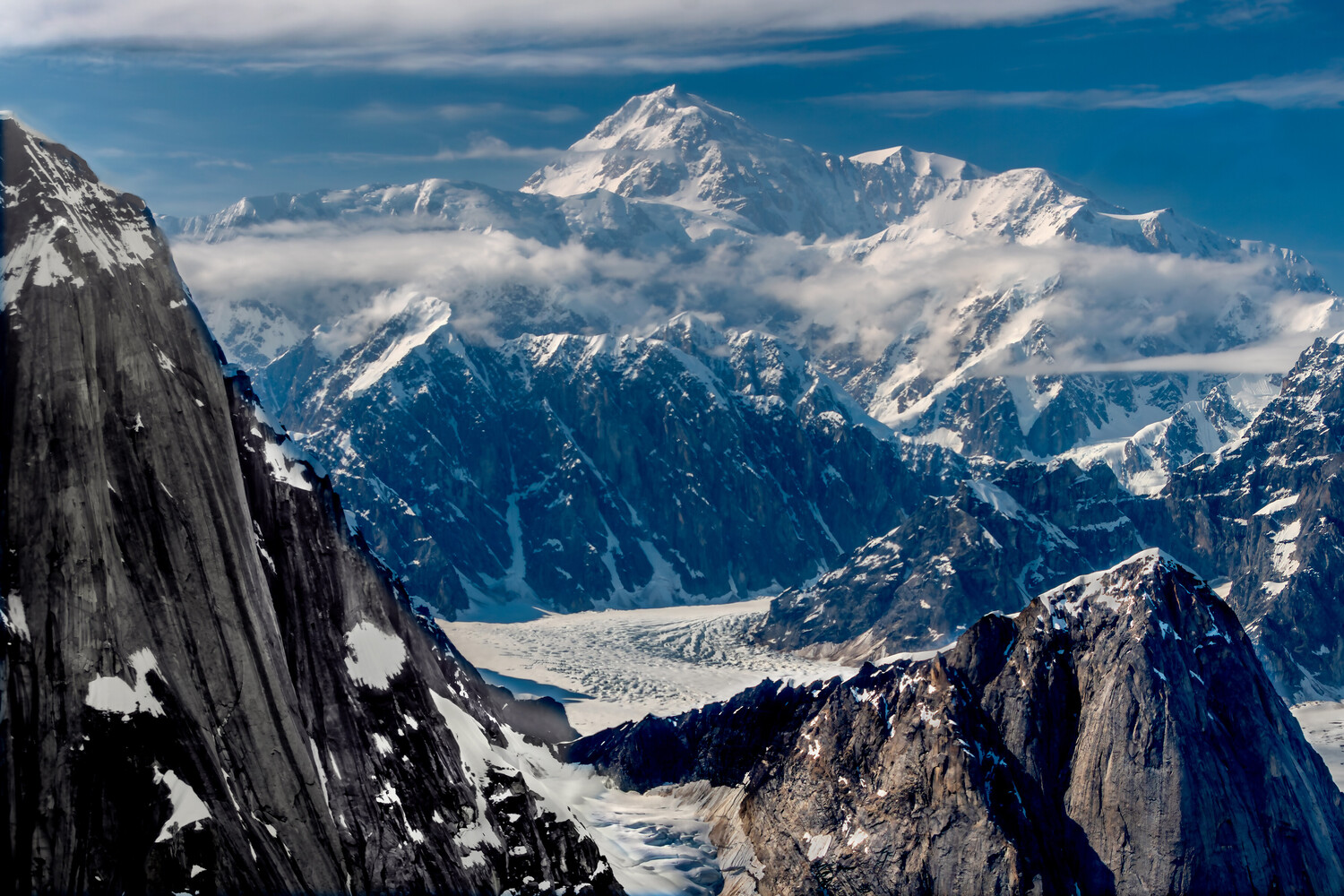 Snow-covered mountain peaks and glaciers viewed from high alpine vantage point with dramatic clouds