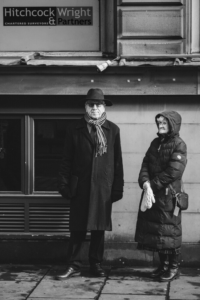Two figures standing against a storefront in a black and white street photograph