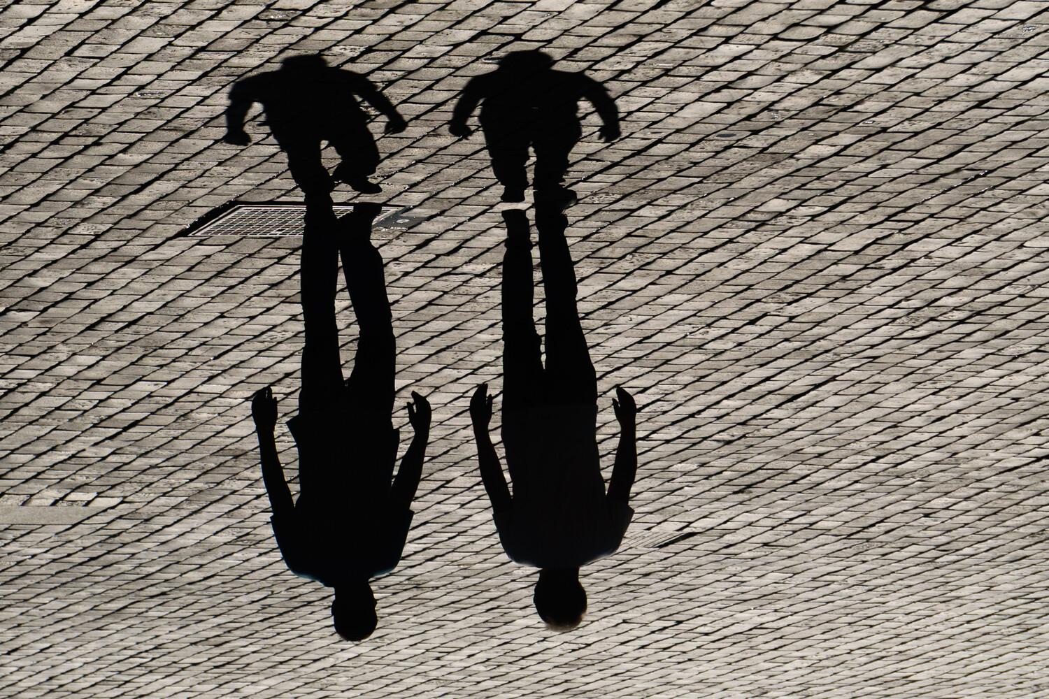 Overhead view of two bicycles casting sharp shadows on textured pavement