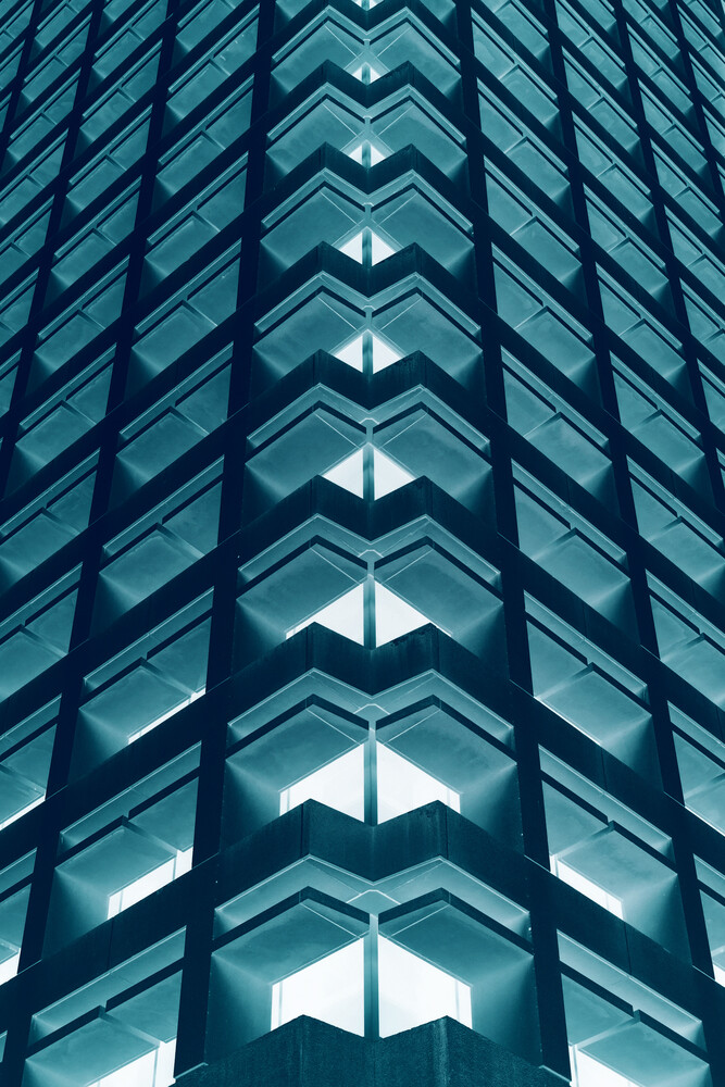 Symmetrical view of modern glass building facade with centered vertical pattern of illuminated windows