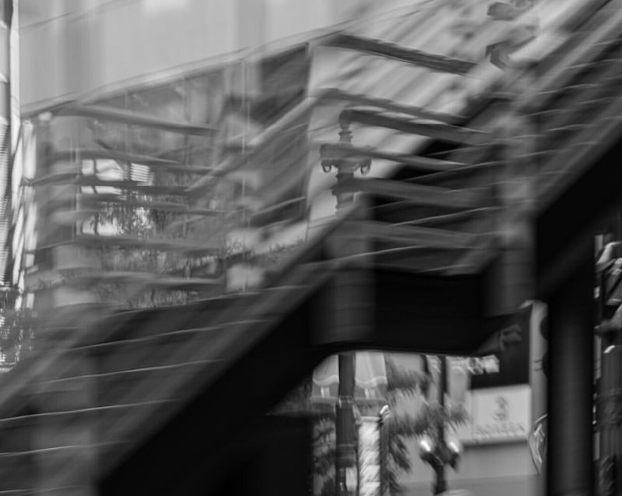 High-contrast black and white photograph with diagonal architectural elements and motion blur