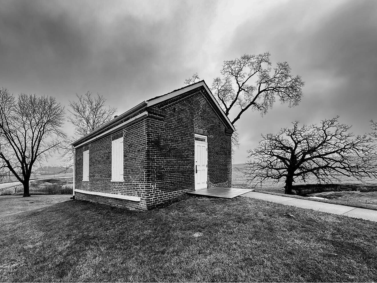 Abandoned brick church with white-trimmed windows standing alone in a barren landscape