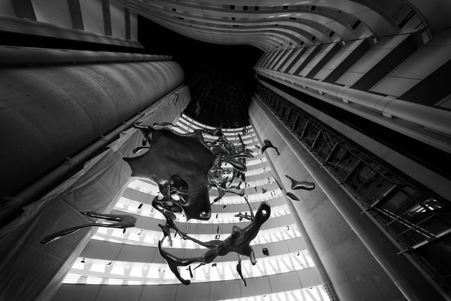 Person suspended mid-air in a narrow vertical urban corridor, shot from below looking up