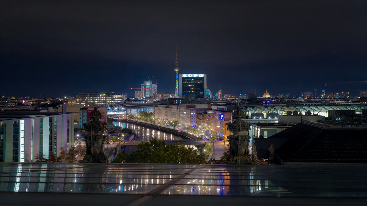 Nighttime cityscape with illuminated buildings reflected in still water